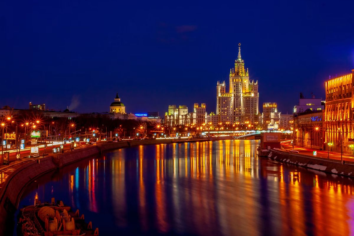 Die Moskwa bei Nacht mit beleuchteten Ufern und einem Hochhaus im Hintergrund