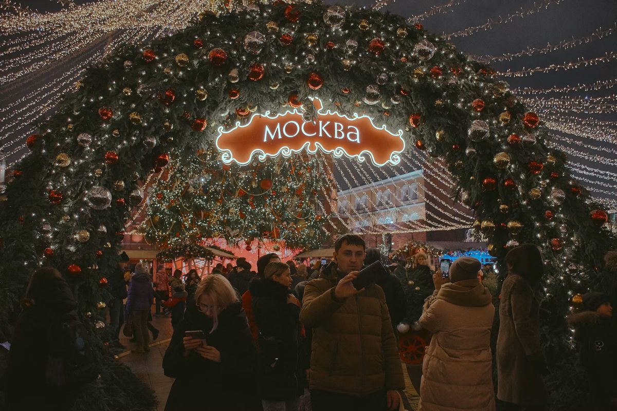 Leuchtender Lichterbogen mit dem kyrillischen Schriftzug Moskwa, darunter Menschen